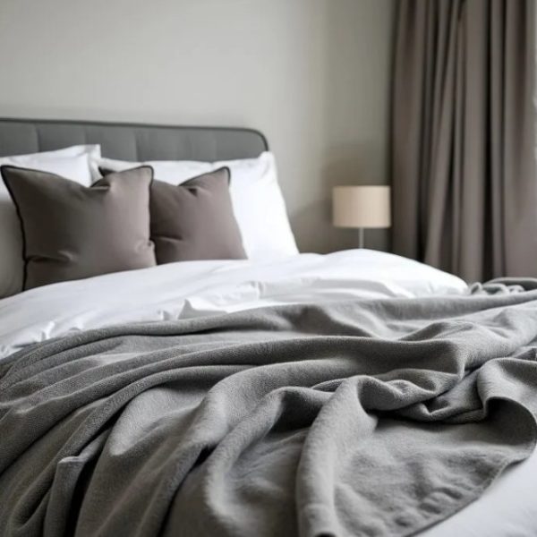 Image shows a bed made up with a Grounding Blanket Sleep & Relaxation Throw